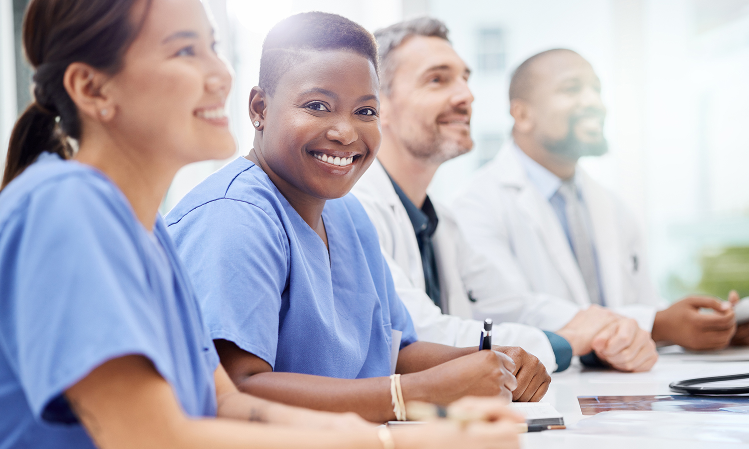 Nurse at meeting table with others smiling at camera
